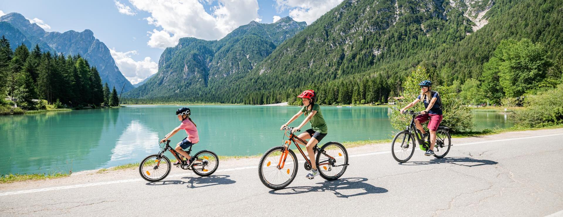 Una donna con due bambini pedala intorno al Lago di Dobbiaco