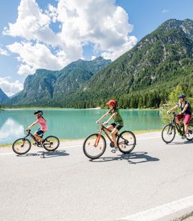 Una donna con due bambini pedala intorno al Lago di Dobbiaco
